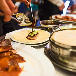 2-PEKING-DUCK-HOUSE-Authentic-Peking-Duck-with-all-the-fixings-seated-tasting a person sitting at a table with a plate of food