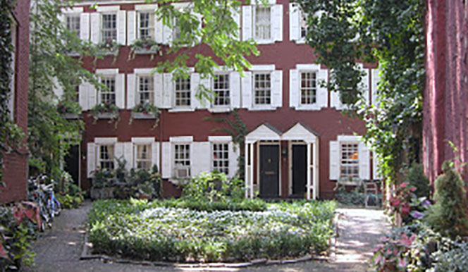 Last-Leaf a close up of a flower garden in front of a brick building