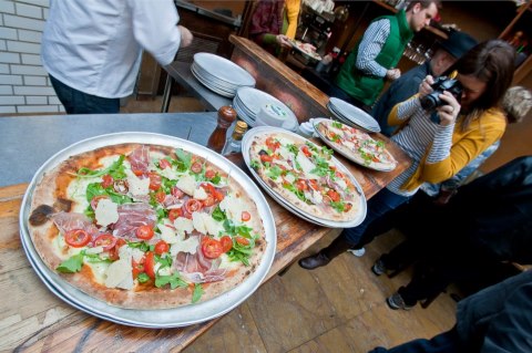 a group of people sitting at a table with a plate of pizza