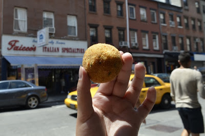 arancini-3 a person holding a surf board on a city street