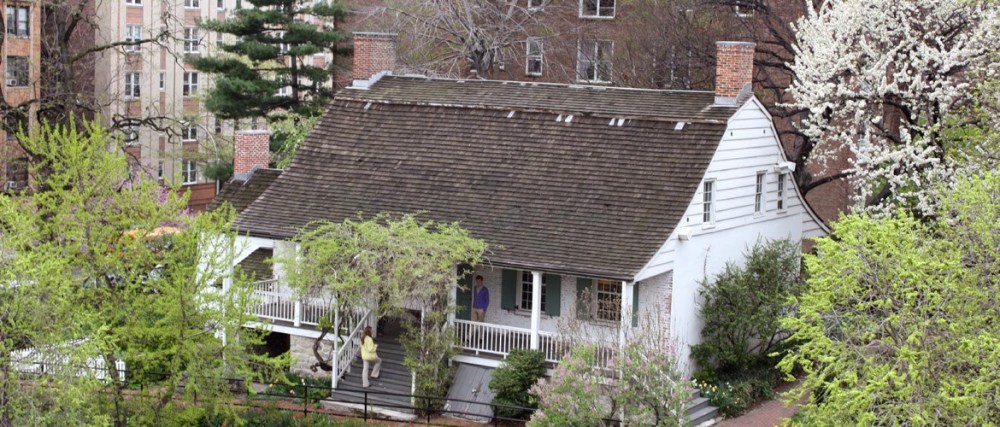 a house with trees in front of a brick building