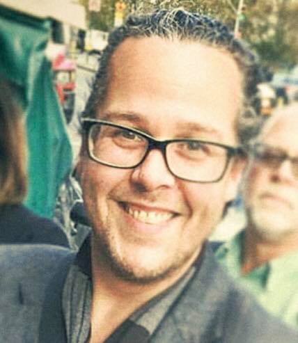 Bert James wearing glasses and smiling at the camera