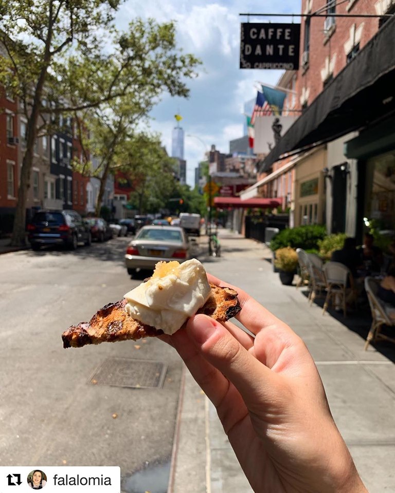 a close up of a person holding a hot dog on a city street