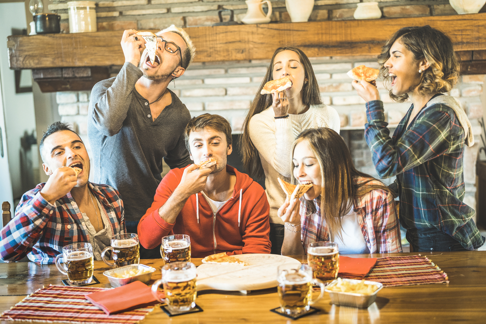Happy friends group eating pizza at chalet restaurant house – Fr a group of people sitting at a table