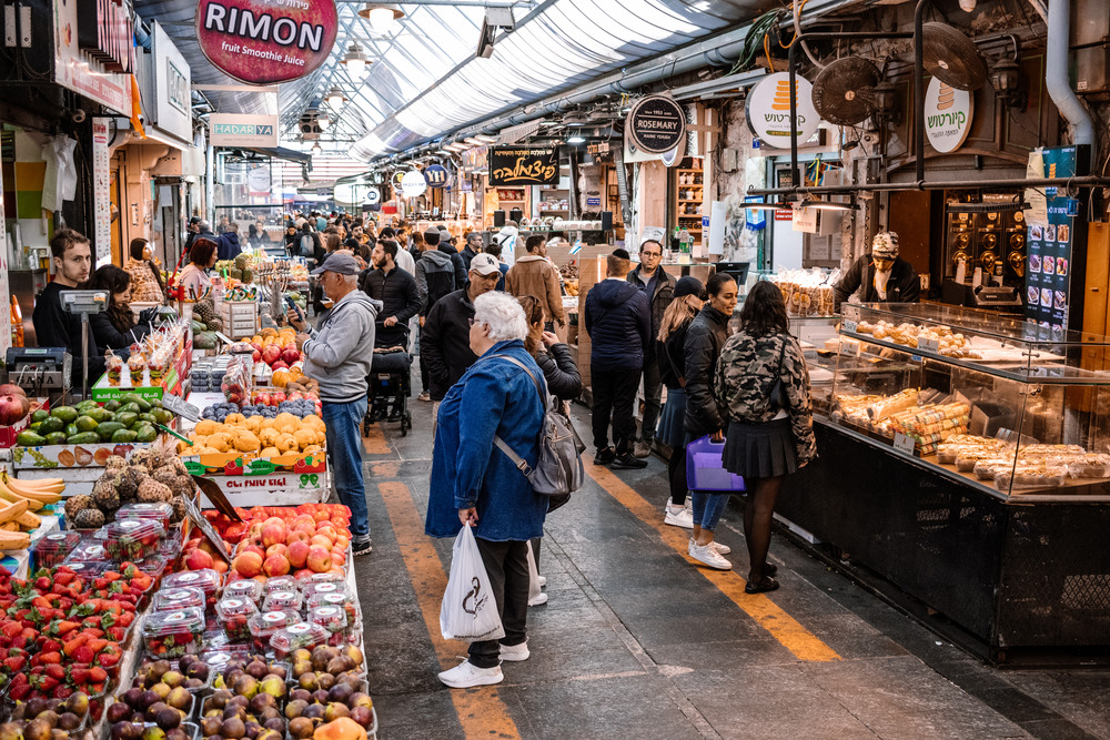 People shopping at Mahane Yehuda Market a group of people at a fruit stand