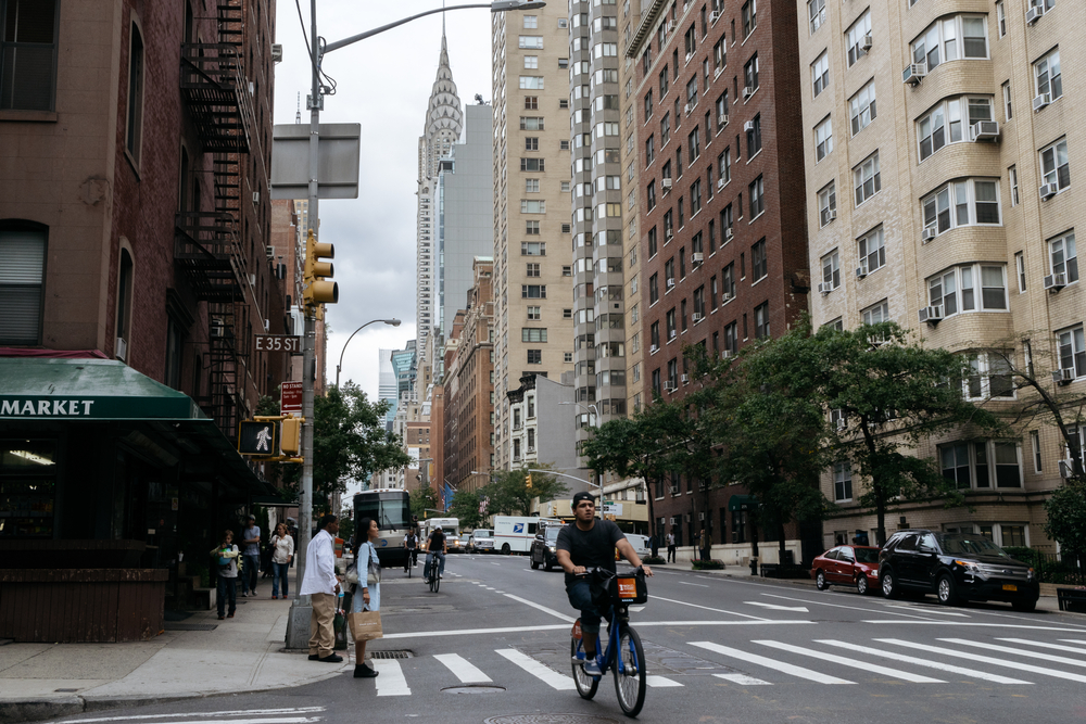 Yellow taxi and people on the street of New York. a group of people riding bikes on a city street