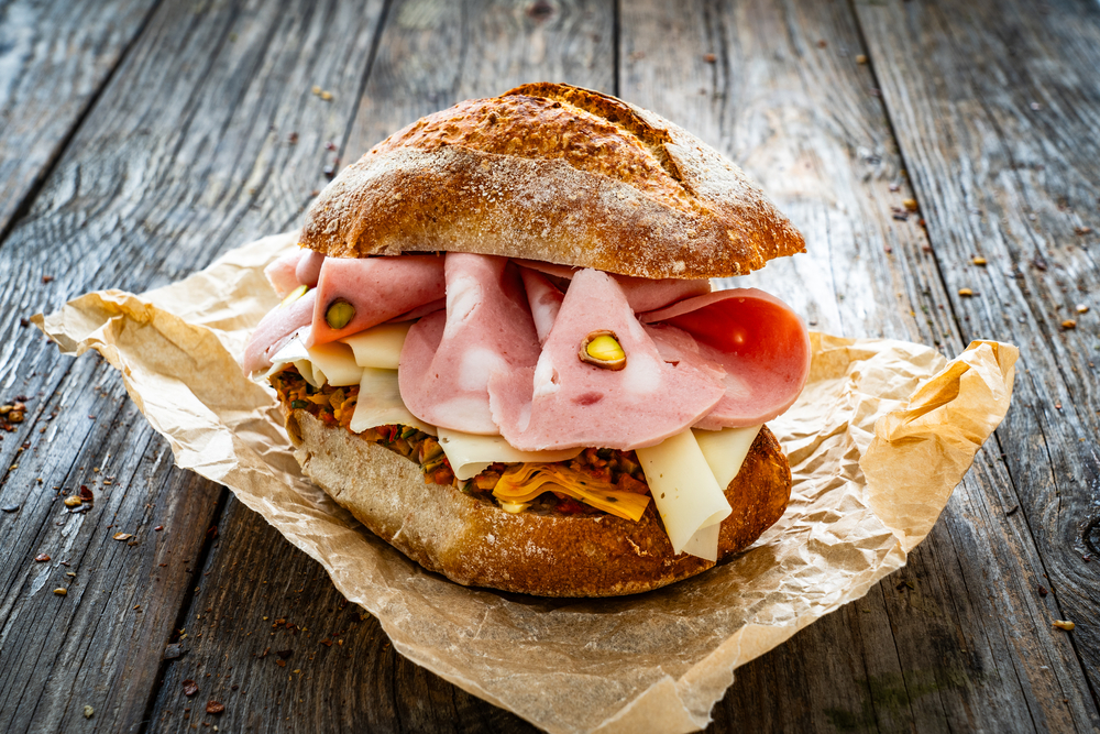 x-best-sandwiches-in-nyc-you-cant-pass-up a cut in half sandwich sitting on top of a wooden cutting board