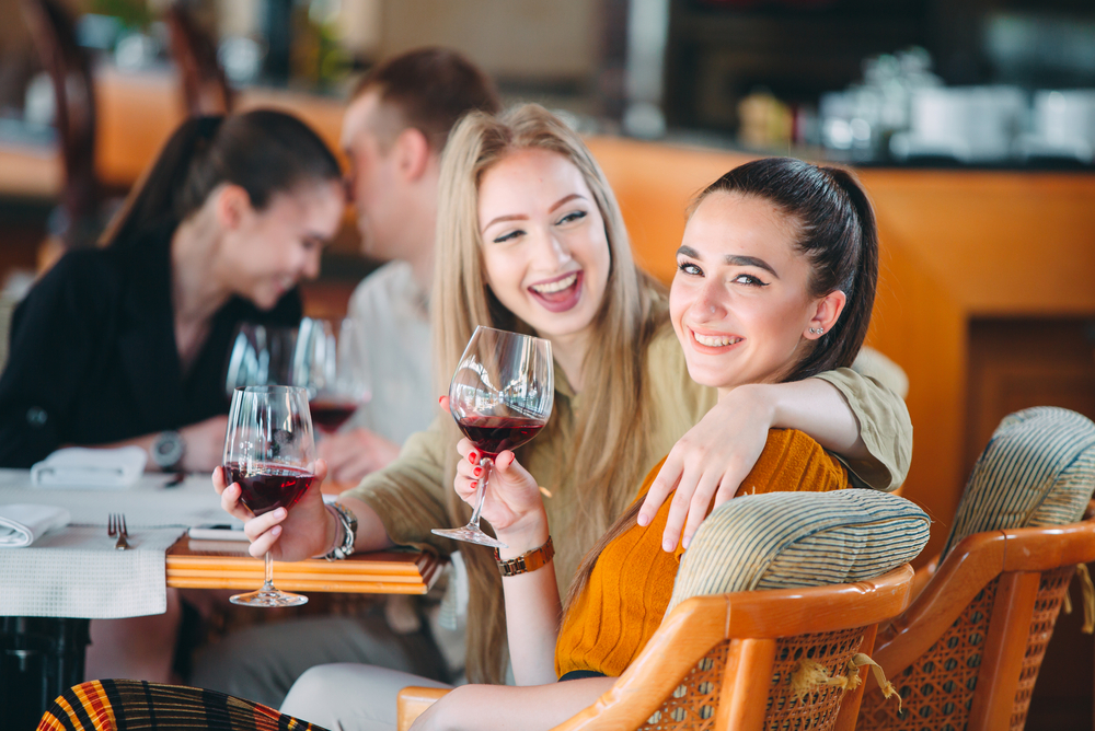 Friends have fun drinking wine, talking and smiling in the restaurant. a group of people sitting at a table