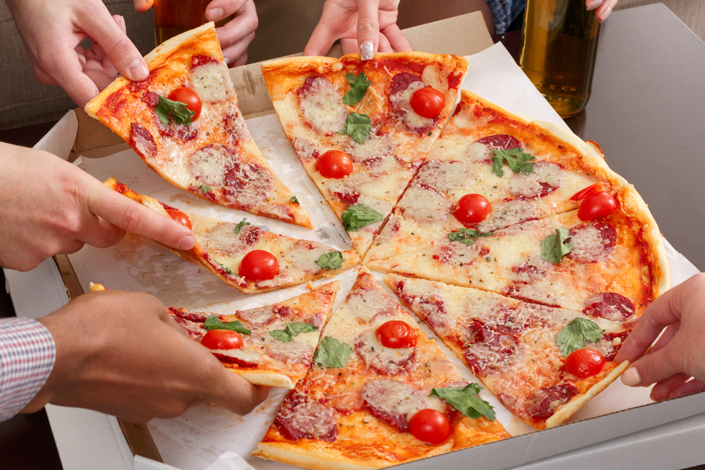 Friends taking slices of pizza from cardboard box a woman eating a slice of pizza