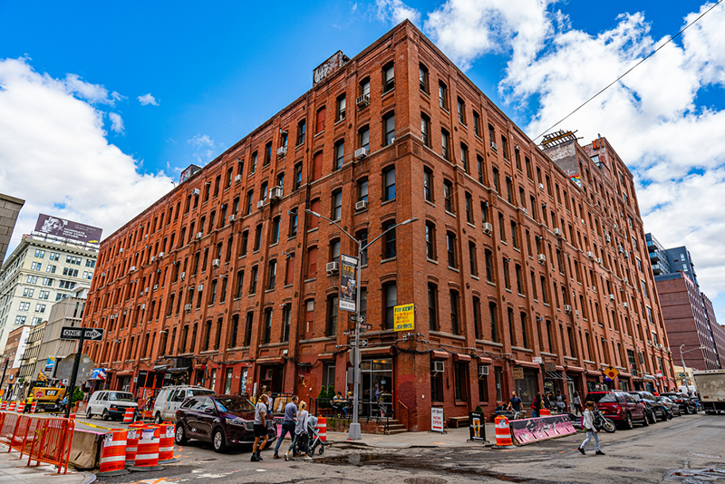 6-oldest-buildings-in-nyc-you-can-still-visit a group of people walking down a street next to tall buildings