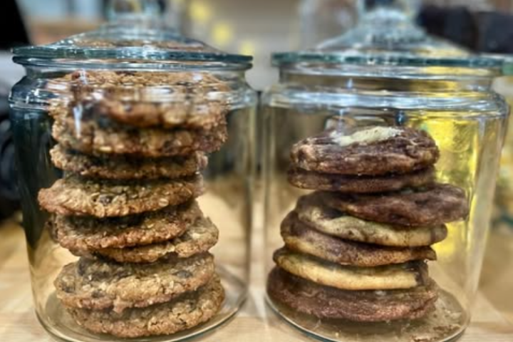 Two glass jars filled with assorted cookies on a counter.