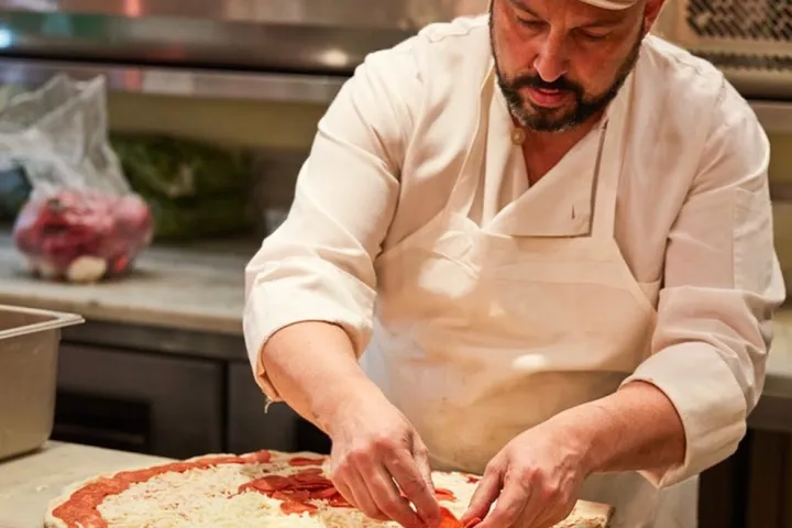 a man is cutting into a pizza