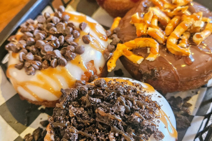 Four decorated donuts in a basket with various toppings.