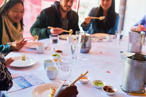 a group of people sitting at a table with a plate of food