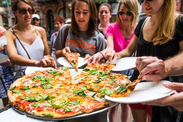 a group of people sitting at a table with a plate of pizza