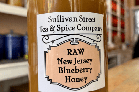 Jar of raw New Jersey blueberry honey from Sullivan Street Tea & Spice Company on a wooden table.