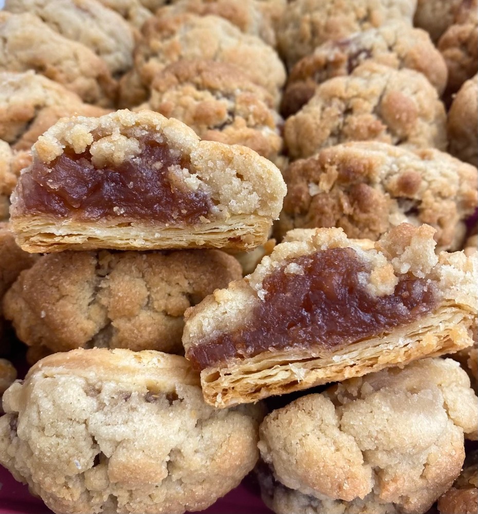 Close-up of crumbly pastries filled with a brown fruit filling, showing layered pastry on the bottom.
