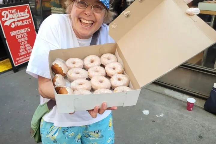 a person holding a box of donuts