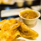 Close-up of roti with a small cup of curry sauce on a plate.