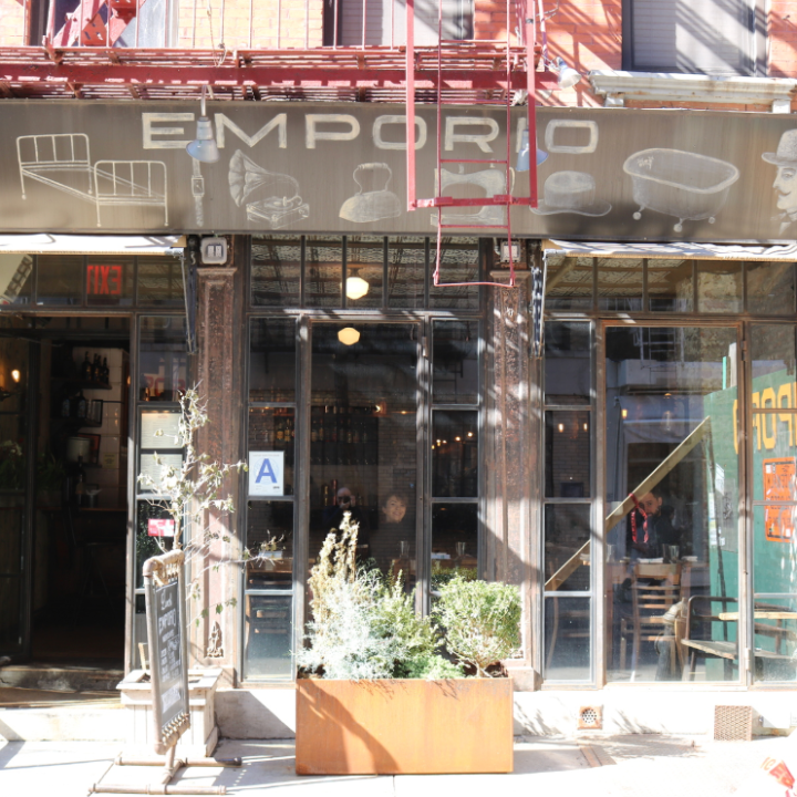 Front view of a vintage-style store with open doors and outdoor plants.