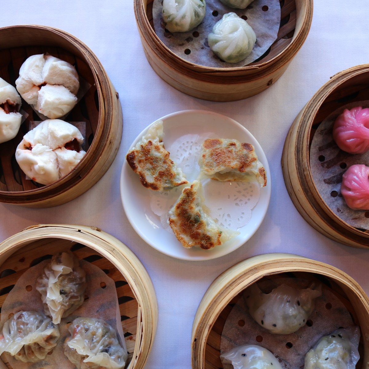 Assorted dim sum in bamboo baskets and dumplings on a plate.