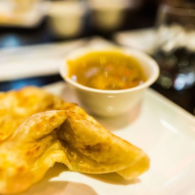 Close-up of flatbread with a bowl of curry on a plate.